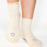 Women wearing off white ankle grip socks with blue happy face for Pilates, Barre, Yoga, and beyond. 