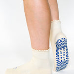 Women wearing off white ankle grip socks with blue happy face for Pilates, Barre, Yoga, and beyond. 