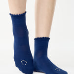 Women wearing navy blue ankle grip socks with white happy face for Pilates, Barre, Yoga, and beyond. 