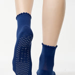 Women wearing navy blue ankle grip socks with white happy face for Pilates, Barre, Yoga, and beyond. 