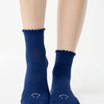 Women wearing navy blue ankle grip socks with white happy face for Pilates, Barre, Yoga, and beyond. 