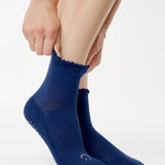 Women wearing navy blue ankle grip socks with white happy face for Pilates, Barre, Yoga, and beyond. 
