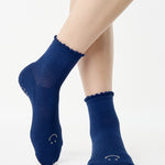 Women wearing navy blue ankle grip socks with white happy face for Pilates, Barre, Yoga, and beyond. 