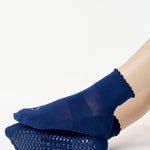 Women wearing navy blue ankle grip socks with white happy face for Pilates, Barre, Yoga, and beyond. 