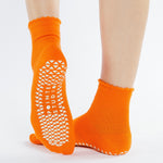 Women wearing orange ankle grip socks with white happy face for Pilates, Barre, Yoga, and beyond. 