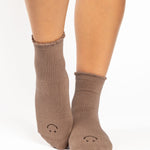 Women wearing brown ankle grip socks with black happy face for Pilates, Barre, Yoga, and beyond. 
