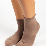 Women wearing brown ankle grip socks with black happy face for Pilates, Barre, Yoga, and beyond. 