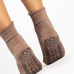 Women wearing brown ankle grip socks with black happy face for Pilates, Barre, Yoga, and beyond. 