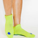 Women wearing a lime full foot grip sock with a blue heart motif on the top made for Pilates, Barre, Yoga, and beyond. 