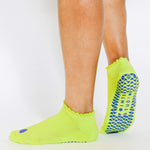 Women wearing a lime full foot grip sock with a blue heart motif on the top made for Pilates, Barre, Yoga, and beyond. 