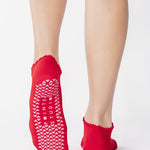 Women wearing a red full foot grip sock with a pink heart motif on the top made for Pilates, Barre, Yoga, and beyond. 