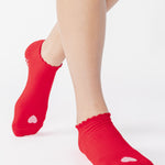 Women wearing a red full foot grip sock with a pink heart motif on the top made for Pilates, Barre, Yoga, and beyond. 