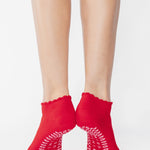 Women wearing a red full foot grip sock with a pink heart motif on the top made for Pilates, Barre, Yoga, and beyond. 