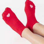 Women wearing a red full foot grip sock with a pink heart motif on the top made for Pilates, Barre, Yoga, and beyond. 