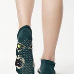 Women wearing a green full foot grip sock with big flowers all around made for pilates, yoga, barre, and beyond.