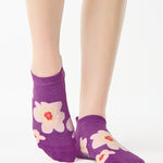 Women wearing a purple full foot grip sock with big flowers all around. 
