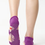 Women wearing a purple full foot grip sock with big flowers all around. 