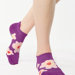Women wearing a purple full foot grip sock with big flowers all around. 