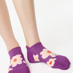 Women wearing a purple full foot grip sock with big flowers all around. 