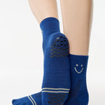 Women wearing navy blue ankle grip socks with white happy face for running. 