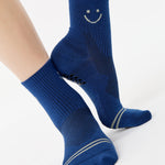 Women wearing navy blue ankle grip socks with white happy face for running. 
