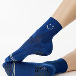 Women wearing navy blue ankle grip socks with white happy face for running. 