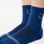 Women wearing navy blue ankle grip socks with white happy face for running. 