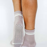Women wearing a solid light purple ankle grip sock with white stripes on the toes and top ankle cuff made for Pilates, Barre, Yoga, and beyond. 