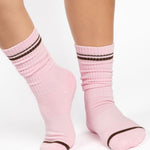 Women wearing a baby pink crew grip sock with dark brown stripes on the toes and top ankle cuff made for Pilates, Barre, Yoga, and beyond. 