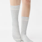 Women wearing a heather grey crew grip sock with white stripes on the toes and top ankle cuff made for Pilates, Barre, Yoga, and beyond. 