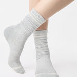 Women wearing a heather grey crew grip sock with white stripes on the toes and top ankle cuff made for Pilates, Barre, Yoga, and beyond. 