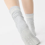 Women wearing a heather grey crew grip sock with white stripes on the toes and top ankle cuff made for Pilates, Barre, Yoga, and beyond. 