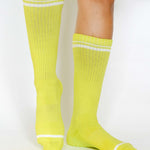 Women wearing a solid lime yellow crew grip sock with white stripes on the toes and top ankle cuff made for Pilates, Barre, Yoga, and beyond. 