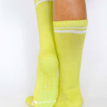 Women wearing a solid lime yellow crew grip sock with white stripes on the toes and top ankle cuff made for Pilates, Barre, Yoga, and beyond. 
