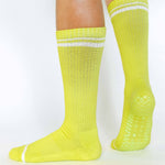 Women wearing a solid lime yellow crew grip sock with white stripes on the toes and top ankle cuff made for Pilates, Barre, Yoga, and beyond. 