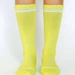 Women wearing a solid lime yellow crew grip sock with white stripes on the toes and top ankle cuff made for Pilates, Barre, Yoga, and beyond. 