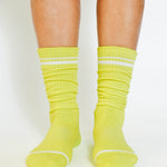 Women wearing a solid lime yellow crew grip sock with white stripes on the toes and top ankle cuff made for Pilates, Barre, Yoga, and beyond. 