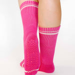 Women wearing a solid hot pink crew grip sock with white stripes on the toes and top ankle cuff made for Pilates, Barre, Yoga, and beyond. 