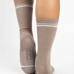 Women wearing a taupe brown crew grip sock with white stripes on the toes and top ankle cuff made for Pilates, Barre, Yoga, and beyond. 