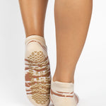 Woman wearing a tan full foot grip sock with brown animal print, made for pilates, barre, yoga, and beyond.  