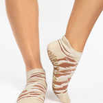 Woman wearing a tan full foot grip sock with brown animal print, made for pilates, barre, yoga, and beyond.  