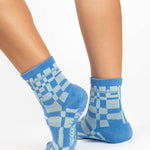 Women wearing an ankle grip sock with a sky blue and light blue checkered design, made for pilates, barre, yoga, and beyond.