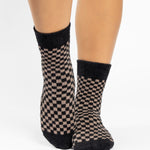 Woman wearing black and brown crew ultra plush soft grip socks made for recovery, post pilates, barre, yoga, and beyond.