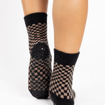 Woman wearing black and brown crew ultra plush soft grip socks made for recovery, post pilates, barre, yoga, and beyond.