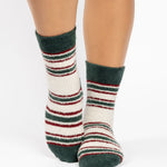 Woman wearing festive white with green and red striped crew ultra plush soft grip socks made for recovery, post pilates, barre, yoga, and beyond.
