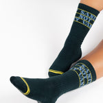 Woman wearing a black crew grip sock with "Sanity Not Vanity" written on the top cuff area in blue, made for pilates, barre, yoga, and beyond.