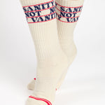 Woman wearing an off white crew grip sock with "Sanity Not Vanity" written on the top cuff area in blue, made for pilates, barre, yoga, and beyond.