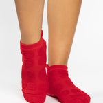 Women wearing red smiley face patterned grip socks made for Pilates, Barre, Yoga, and beyond. 