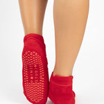 Women wearing red smiley face patterned grip socks made for Pilates, Barre, Yoga, and beyond. 