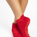 Women wearing red smiley face patterned grip socks made for Pilates, Barre, Yoga, and beyond. 